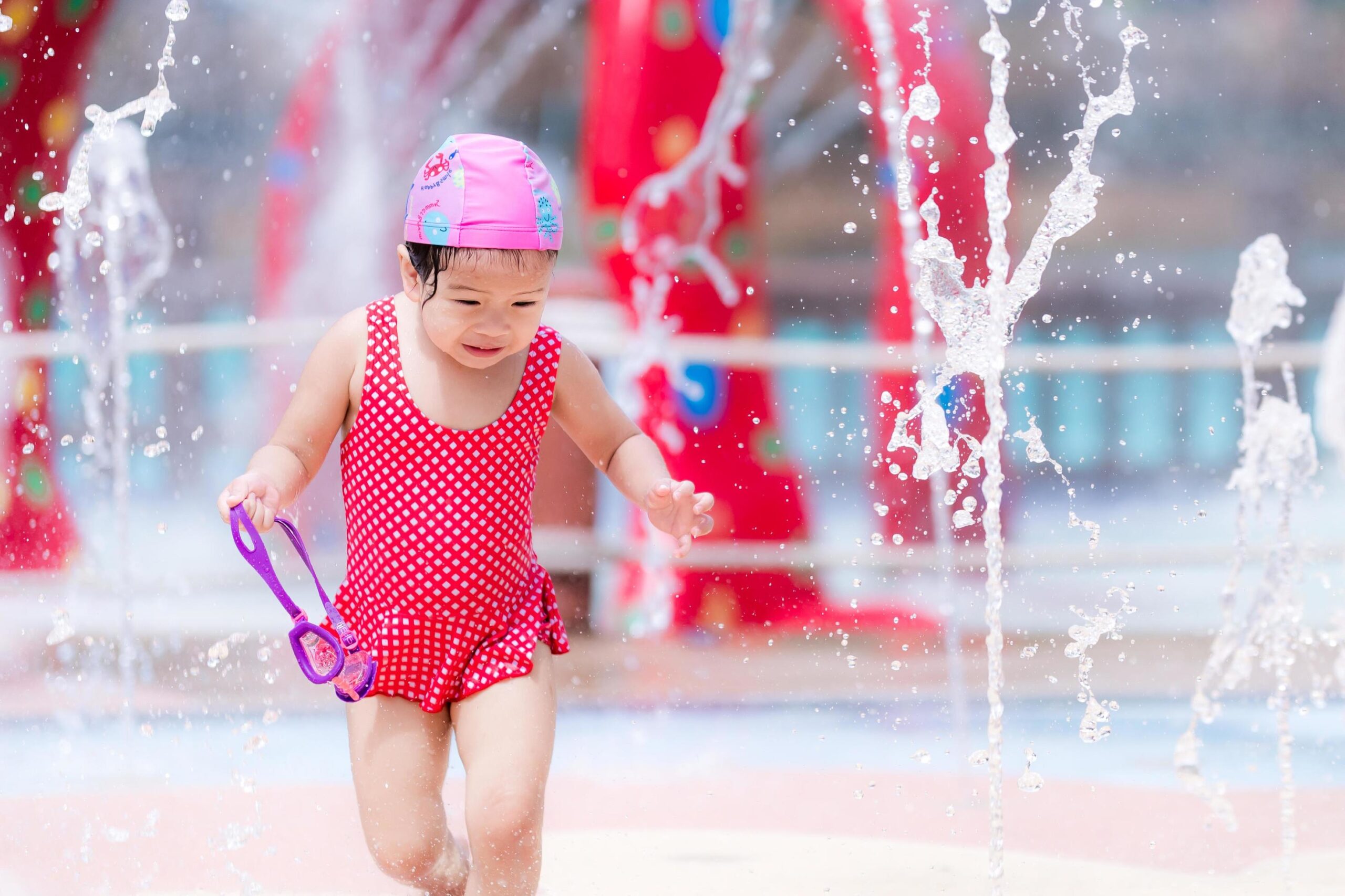 Front Page -Twinkle Tots happy little child play with water to cool dancing with fountain at water park in summer or spring girl has fun playing in water fountains kid wear red swimsuit baby aged 3 years old free photo scaled